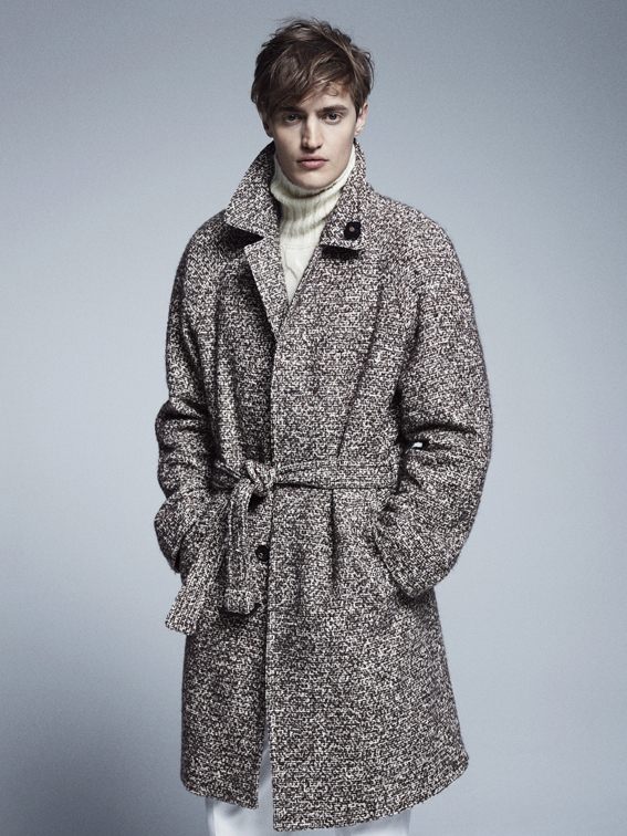 Cappotto in lana chiné sui toni del marrone indossato su un pantalone in velluto a coste e dolcevita a treccia in lana mohair.